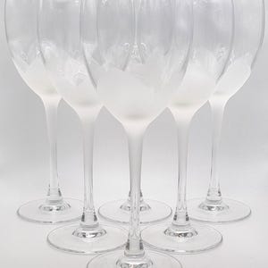 May include: Set of six clear glass wine glasses with a frosted finish. The glasses have a tall, slender stem and a wide bowl.
