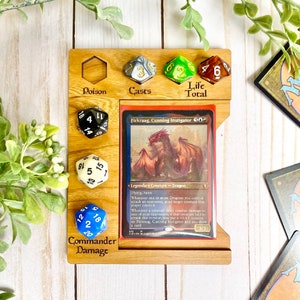 May include: Wooden game board with compartments for dice and a card. The card is a Magic: The Gathering card for Firkraag, Cunning Instigator. The board has labels for Poison, Casts, Life Total, and Commander Damage.