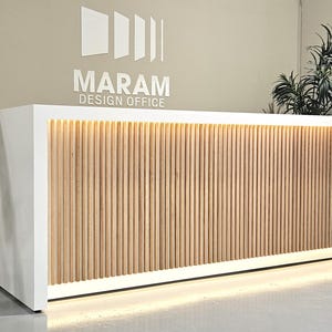 May include: White reception desk with a wood slat panel and a MARAM DESIGN OFFICE logo above it.
