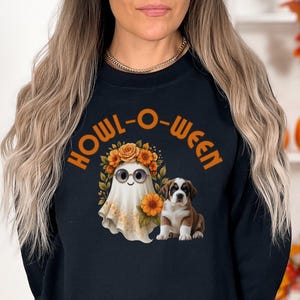 May include: Black sweatshirt with the text "HOWL-O-WEEN" in orange. The graphic features a ghost wearing a floral crown and sunglasses, and a brown and white puppy. The design has a Halloween theme.