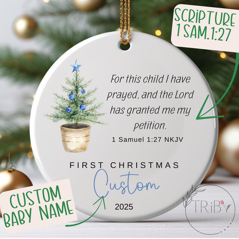 May include: Round white Christmas ornament with a gold hanging loop. It features a watercolour illustration of a Christmas tree with blue baubles. Text includes "First Christmas", "Custom", "2025", and a Bible verse.