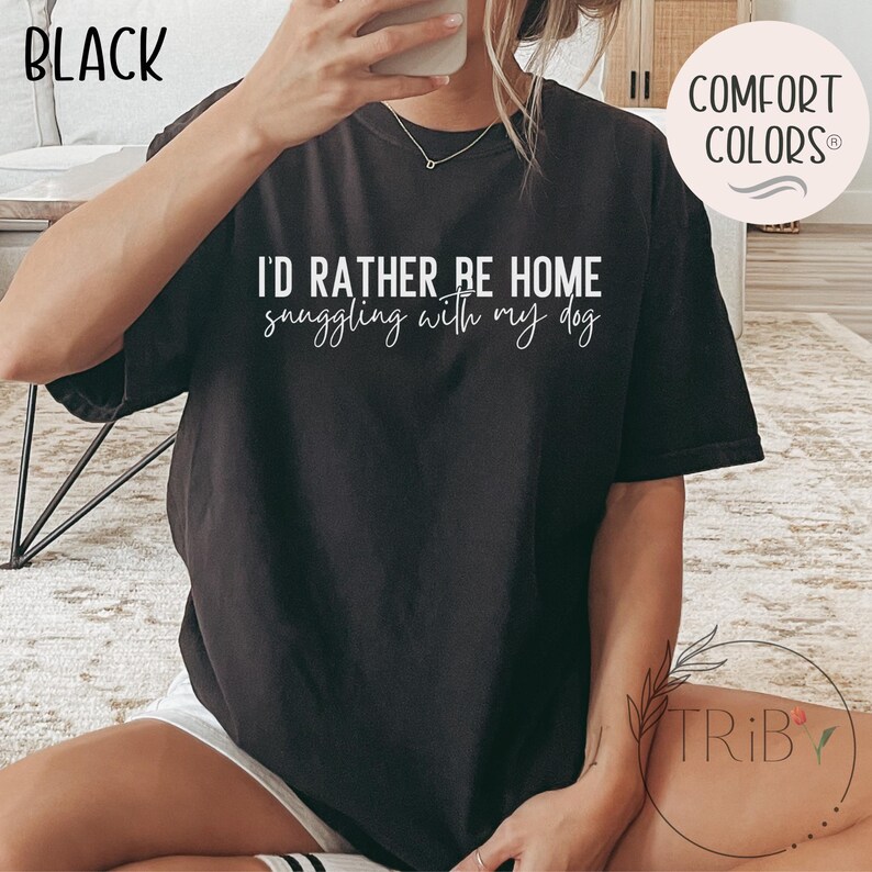 May include: Black t-shirt with the text "I'D RATHER BE HOME snuggling with my dog" in white script. The shirt is a Comfort Colors brand. The word "BLACK" is in the upper left corner.