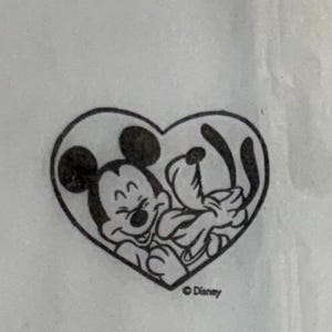 May include: Black and white illustration of Mickey Mouse and Pluto inside a heart-shaped outline. Mickey Mouse is smiling, and Pluto is playfully interacting. The Disney logo is in the bottom right corner.