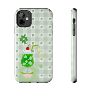 May include: A phone case featuring a green and white gingham pattern with shamrocks. The design includes a green drink with ice cubes, a cherry, and a straw. The case is designed to fit a smartphone.