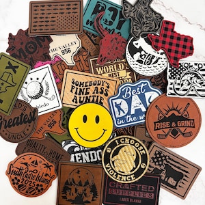Peut inclure: Une collection de patchs en cuir variés, de différentes formes et couleurs. Les patchs présentent des motifs tels qu'un smiley, des contours de l'État du Texas, des graphiques sur le thème du golf et du texte comme "Rise & Grind".