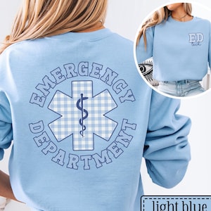 May include: Light blue sweatshirt with "Emergency Department" text and a medical symbol on the back. The medical symbol is a blue and white gingham pattern with a caduceus in the center. The front of the sweatshirt has "ED tech" text.