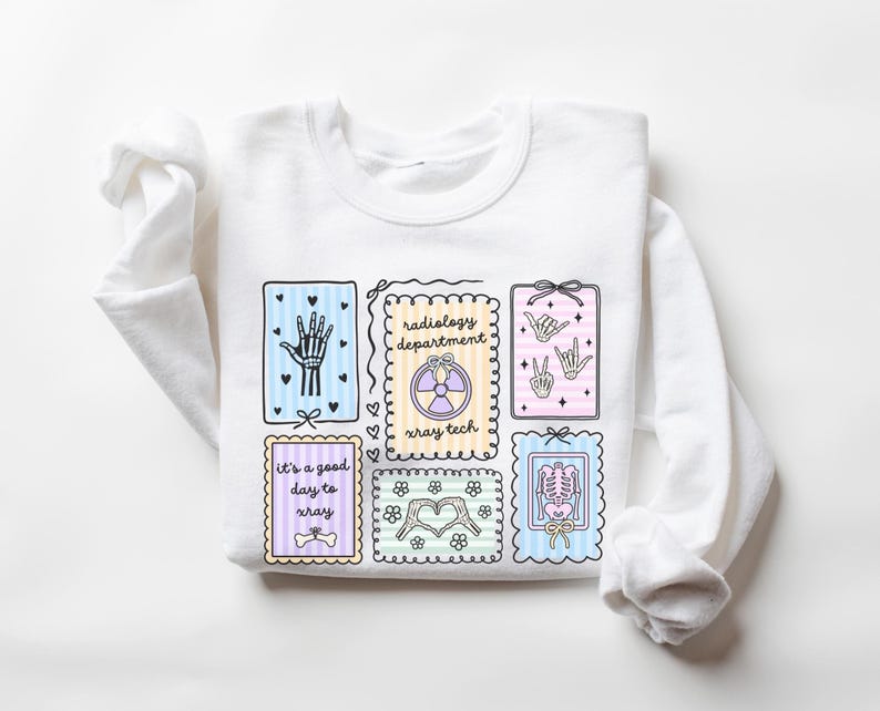 May include: White sweatshirt featuring colorful illustrations related to radiology. The design includes images of a hand, a skeleton, and a radiology symbol, along with the text "radiology department" and "It's a good day to xray."