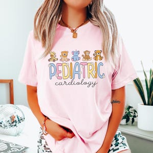May include: Pink t-shirt with a graphic of cartoon animals and the text "PEDIATRIC cardiology".