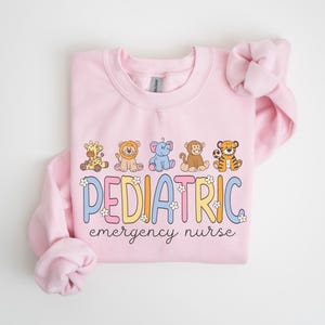 May include: Pink sweatshirt with a graphic of animals and the text "PEDIATRIC emergency nurse".