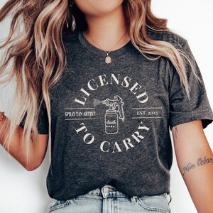 Spray Tan Artist Shirt • Licensed To Carry Spray Tan Artist Work Tshirt • Personalized Spray Tan Tech EST. 2025 Gift • Sunless Tanning Salon Dark Grey Heather