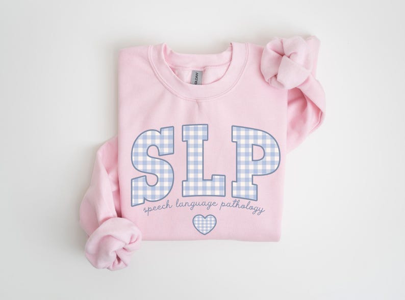 May include: Pink sweatshirt with a blue and white gingham pattern spelling "SLP" and the text "speech language pathology" below. A small heart is centered below the text.