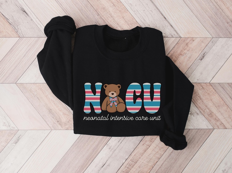 Puede incluir: Camiseta negra de manga larga con un gr&aacute;fico de un osito de peluche y el texto "NCU neonatal intensive care unit".