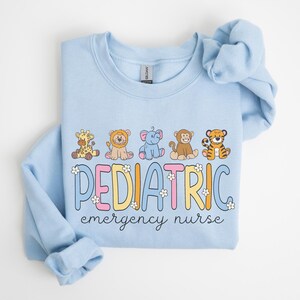 May include: Light blue sweatshirt with a graphic of cartoon animals and the text "PEDIATRIC emergency nurse".