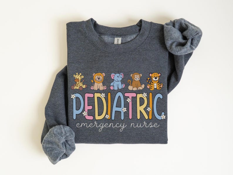 May include: A dark gray sweatshirt with the text "PEDIATRIC emergency nurse" in colorful letters with flowers. The text is surrounded by five cartoon animals: a giraffe, a lion, an elephant, a monkey, and a tiger.