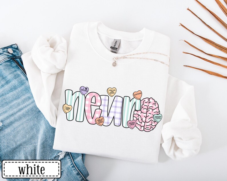 May include: White sweatshirt with the word "neuro" in a colorful, playful font, accompanied by a brain graphic and heart-shaped candies. The candies have phrases like "love on brain" and "caffeine". The word "white" is in a white rectangle.