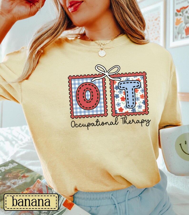 May include: A light yellow t-shirt featuring the letters "OT" in a postage stamp design. The "O" is red with a white and blue gingham pattern, and the "T" is blue with red and white floral accents. The words "Occupational Therapy" are printed below.