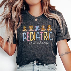 May include: A dark grey t-shirt with a colourful graphic that says "PEDIATRIC cardiology" with cartoon animals. The animals are a giraffe, a lion, an elephant, a monkey, and a tiger.