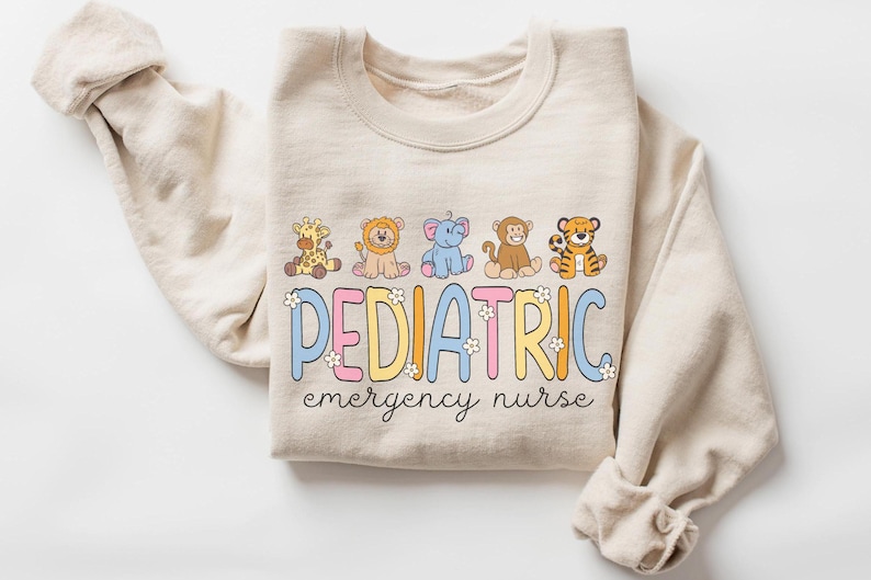 May include: A beige sweatshirt with a graphic of cartoon animals and the text "PEDIATRIC emergency nurse".