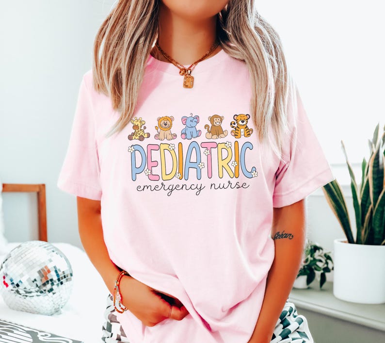 May include: Pink t-shirt with a graphic of cartoon animals and the text "PEDIATRIC emergency nurse".