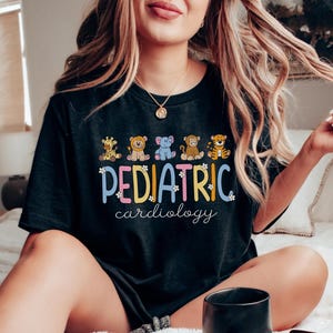 May include: Black t-shirt with a colourful graphic of animals and the text "PEDIATRIC cardiology".