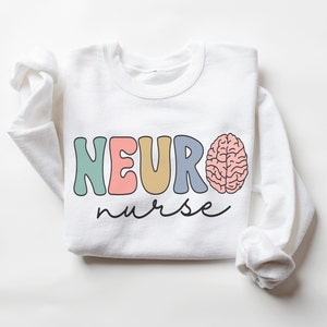 Puede incluir: Sudadera blanca con el texto "NEURO nurse" en letras de colores y un gr&aacute;fico de cerebro rosa.