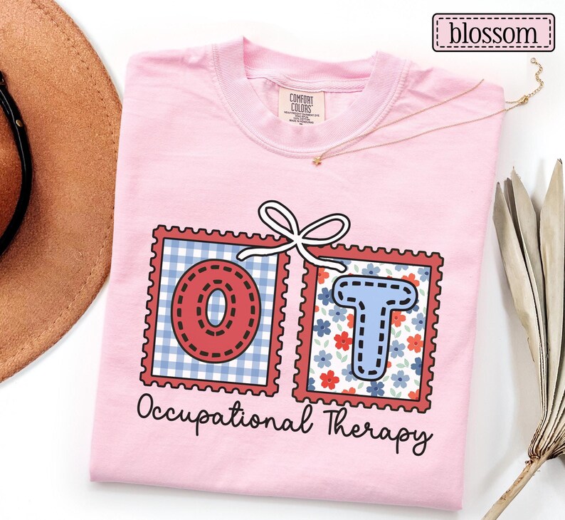 May include: A light pink t-shirt with the words "OT Occupational Therapy" printed on the front. The letters "OT" are inside of red postage stamp designs. The "O" is red with a dotted design, and the "T" is blue with a floral pattern.