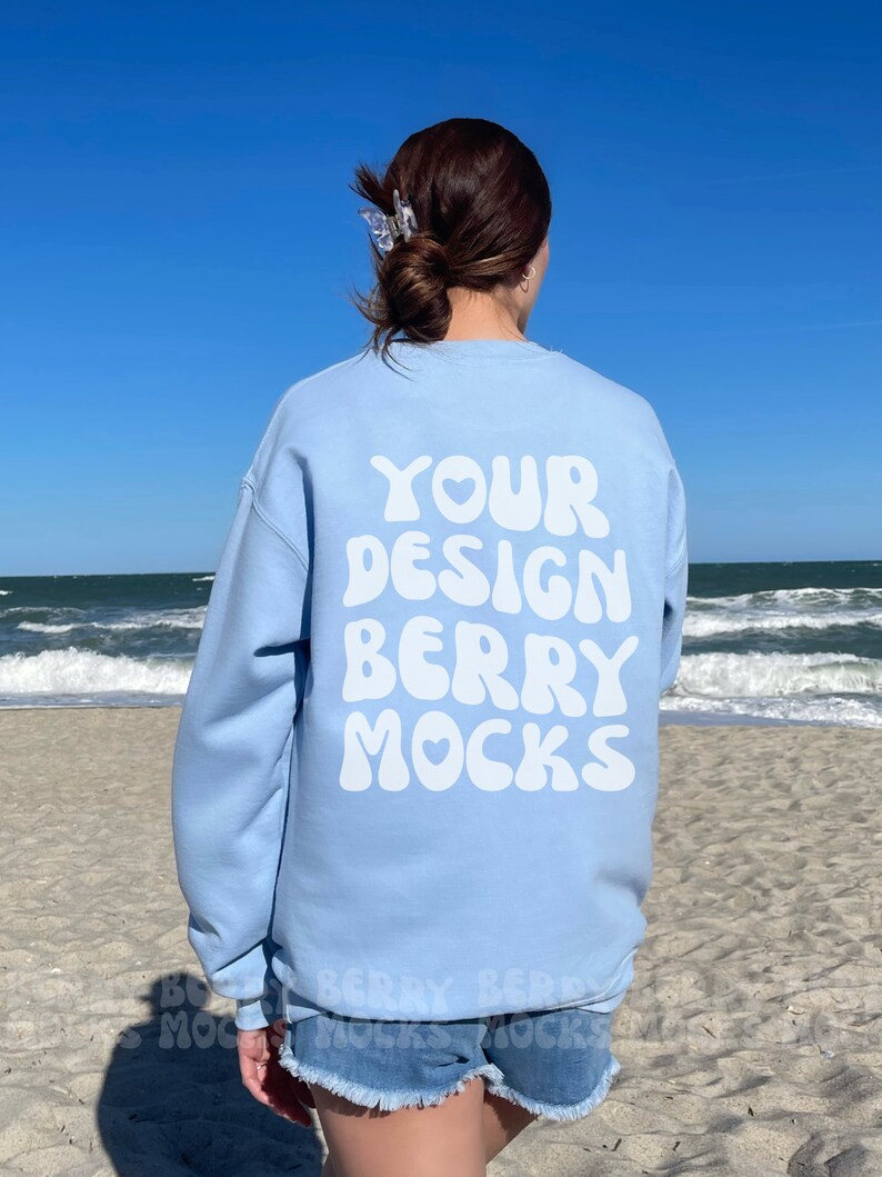 May include: A light blue sweatshirt with the text "YOUR DESIGN BERRY MOCKS" printed on the back in white bubble letters.