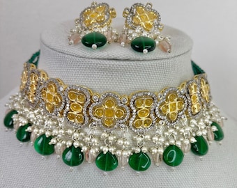 May include: A gold and silver choker necklace with green and white beads. The necklace has a floral design and is accented with small pearls. The necklace comes with a matching pair of earrings.