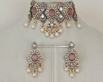 Könnte beinhalten: Eine silberne und rosafarbene Choker-Halskette mit Perlenakzenten und passenden Ohrringen. Die Halskette hat einen großen rosafarbenen Stein in der Mitte jedes Anhängers. Die Ohrringe haben ein ähnliches Design mit einem kleineren rosafarbenen Stein.