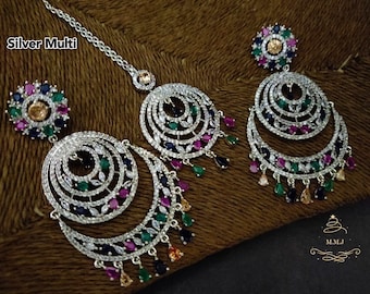 Puede incluir: Pendientes de plata multicolores con un diseño circular y piedras colgantes en forma de lágrima. Los pendientes están adornados con pequeñas piedras de colores. Los pendientes forman parte de un conjunto de joyas que incluye un collar a juego.