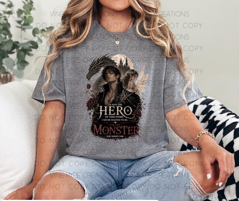 May include: A gray t-shirt featuring a graphic design with the text "I'm not the hero of this story, I never wanted to be... I'm the monster you wrote for." The design includes a dark-haired figure, a fairy, and roses.