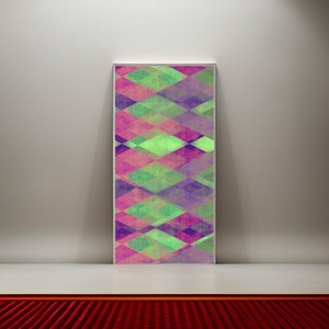 Op de afbeelding: Abstracte geometrische kunstprint met een kleurrijk ruitpatroon in tinten roze, groen en paars. De print is ingelijst en hangt aan een witte muur.