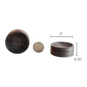 May include: Dark wood coaster with a spiral design. The coaster is 2 inches in diameter and 0.75 inches tall. A coin is next to the coaster for size comparison. The coaster is made of dark wood.
