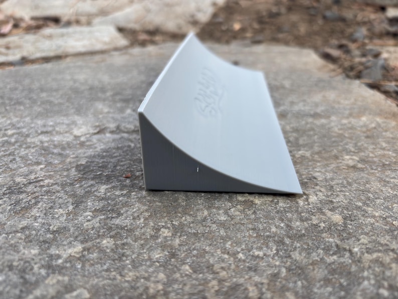 Puede incluir: Una rampa de pl&aacute;stico gris para fingerboard, con las palabras "24/7 Skate" impresas en el lateral.