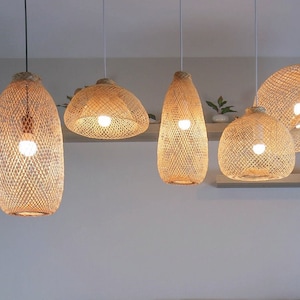 Puede incluir: Un sofá seccional gris con varios cojines se encuentra en una sala de estar con una alfombra blanca. La habitación está decorada con varias lámparas colgantes tejidas que cuelgan del techo.