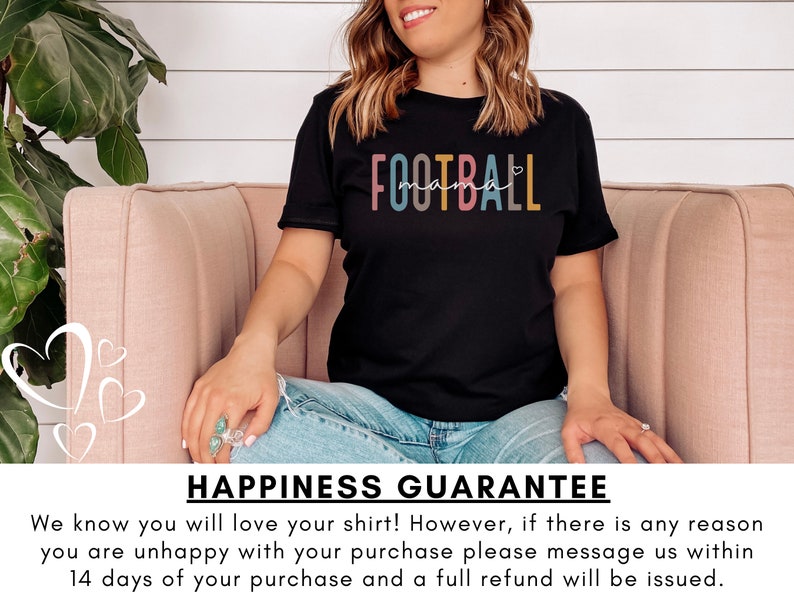 Op de afbeelding: Een zwart T-shirt met de tekst "FOOTBALL mama" in regenboogkleuren. De tekst is in een speels lettertype met een hartje. Het shirt wordt gedragen door iemand die op een roze bank zit.