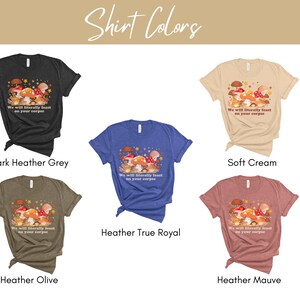 Op de afbeelding: Vijf verschillende t-shirts in verschillende kleuren met een paddenstoel afbeelding en de tekst "We will literally feast on your corpse". De kleuren zijn donker grijs melange, zachte cr&egrave;me, heideblauw melange, olijf melange en heidepaars melange.