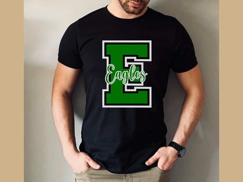 Puede incluir: Camiseta negra con una letra "E" verde y la palabra "Eagles" en letras blancas. La letra "E" est&aacute; delineada en blanco.