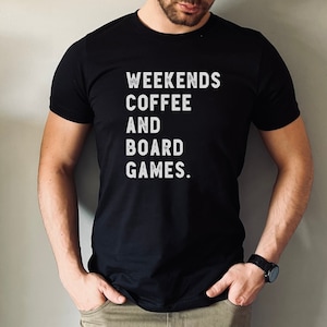 May include: A black t-shirt with white text that reads "Weekends Coffee and Board Games."
