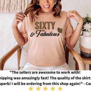 May include: A peach-colored t-shirt with the text "SIXTY & Fabulous" in black lettering. The word "SIXTY" is decorated with a leopard print pattern.