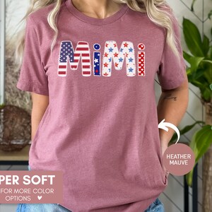 K&ouml;nnte beinhalten: Ein T-Shirt in Heide-Mauve mit dem Wort "MIMI" in den patriotischen Farben Rot, Wei&szlig; und Blau. Die Buchstaben sind mit Sternen und Streifen verziert. Das Shirt ist superweich und in anderen Farben erh&auml;ltlich.