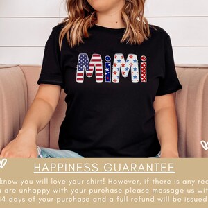 K&ouml;nnte beinhalten: Ein schwarzes T-Shirt mit dem Wort "MIMI" in Rot, Wei&szlig; und Blau, mit einem rot-wei&szlig;-blauen Sternenmuster. Das Shirt liegt auf einem rosa Sofa mit wei&szlig;en Herzen im Hintergrund. Zufriedenheitsgarantie. Wir wissen, dass Sie Ihr Shirt lieben werden! Wenn Sie jedoch aus irgendeinem Grund mit Ihrem Kauf nicht zufrieden sind, senden Sie uns bitte innerhalb von 14 Tagen nach Ihrem Kauf eine Nachricht und Sie erhalten eine volle R&uuml;ckerstattung.