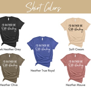 May include: Five t-shirts in different colors with the text "I'd rather be off-roading" printed in white. The colors are dark heather grey, soft cream, heather true royal, heather olive, and heather mauve.