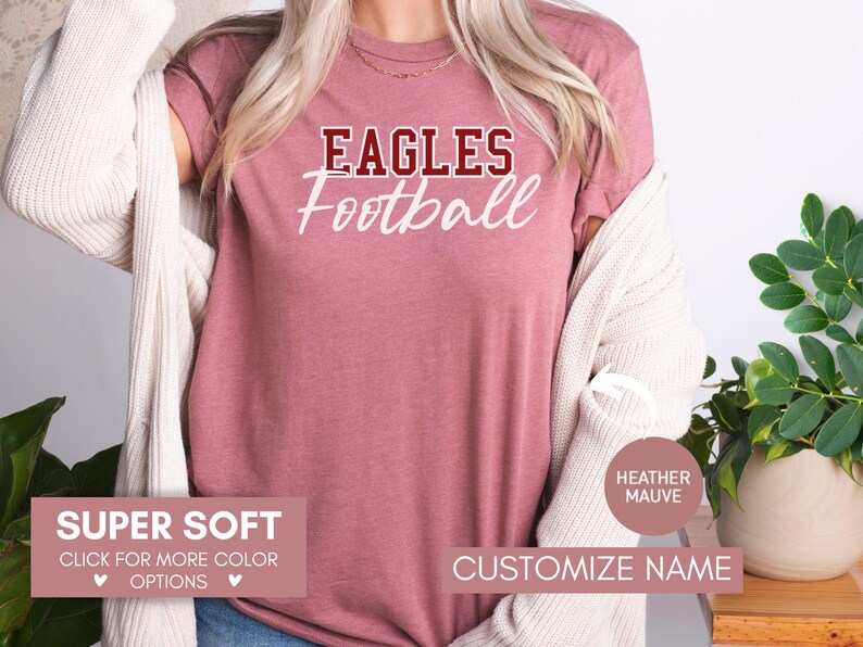 May include: A heather mauve t-shirt with the text "Eagles Football" in white and maroon lettering. The shirt is super soft and available in other colours.