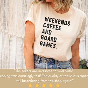 May include: A cream colored t-shirt with black text that reads "Weekends Coffee and Board Games."