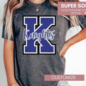 Puede incluir: Una camiseta gris con una gran "K" azul y blanca con la palabra "Knights" en escritura blanca. El texto "SUPER SOFT" y "CLICK FOR MORE COLOR OPTIONS" est&aacute; en la esquina superior derecha de la imagen.