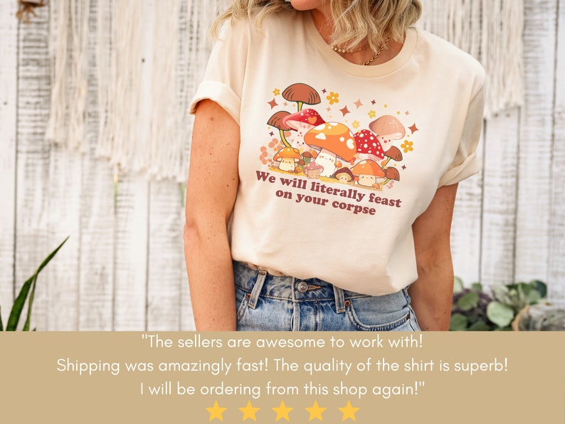 Op de afbeelding: Een beige t-shirt met een afbeelding van paddenstoelen en de tekst "We will literally feast on your corpse".