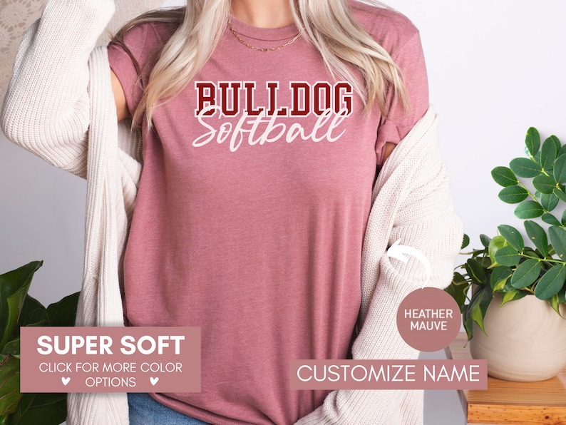 May include: A heather mauve t-shirt with the text "BULLDOG Softball" in white and maroon lettering. The shirt is super soft and available in other colors. Customize the name on the shirt.