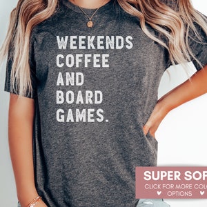 May include: A gray t-shirt with the text "Weekends Coffee and Board Games." printed in white. The shirt is super soft and available in multiple colors.