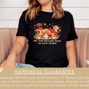 Op de afbeelding: Zwart T-shirt met een afbeelding van paddenstoelen en de tekst "We will literally feast on your corpse".